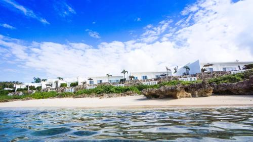 Blick auf einen Strand mit Häusern und das Wasser in der Unterkunft Crystal Villa Miyakojima Sunayama Beach in Miyako-jima