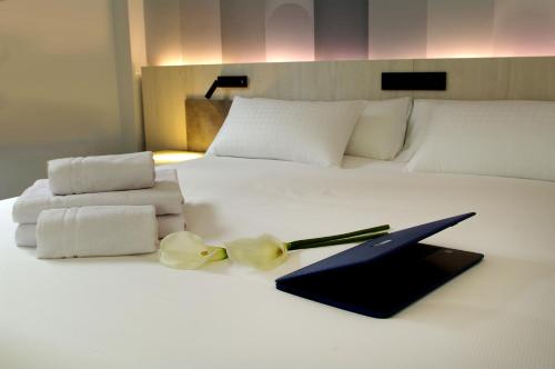 a bed with towels and a folder and flowers on it at Hotel NERU con Encanto in León