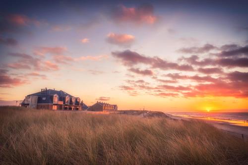 dom na plaży z zachodem słońca w tle w obiekcie Strandhotel Noordzee w mieście De Koog