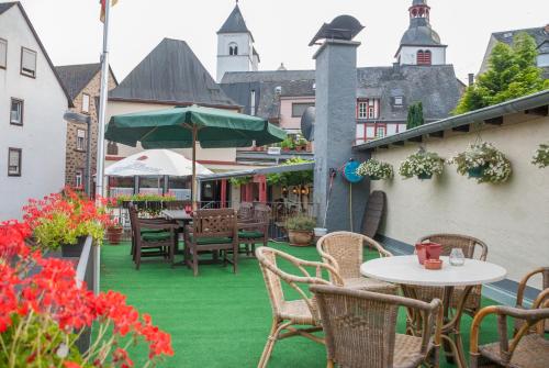 een patio met groen gras en tafels en stoelen bij Alte Weinstube Burg Eltz in Treis-Karden