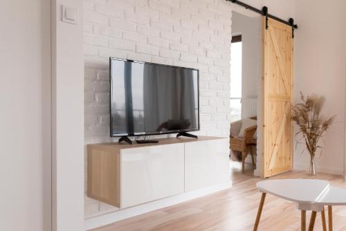 a living room with a flat screen tv on a white brick wall at Eco apartament Nałęczów in Nałęczów