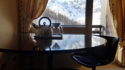 a tea kettle sitting on a table in front of a window at Casa Preziosa - Cielo Alto in Breuil-Cervinia