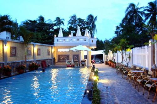 uma piscina ao lado de um edifício com mesas e cadeiras em Thao Ha Mui Ne Hotel em Mui Ne