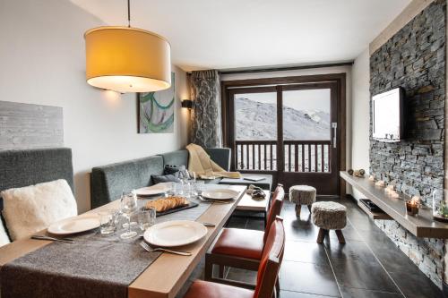 ein Esszimmer mit einem Tisch, Stühlen und einer Steinmauer in der Unterkunft Residence Montana Plein Sud in Val Thorens