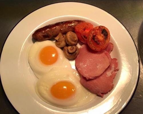 une assiette de nourriture avec des œufs, des saucisses et des champignons dans l'établissement The Black Hole, à Winchester