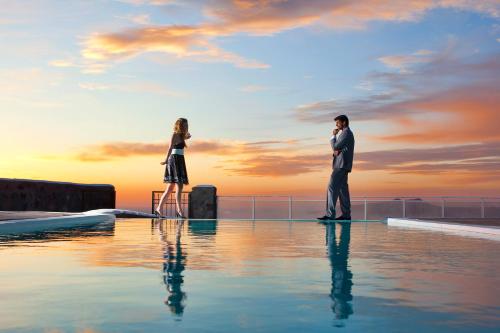 un hombre y una mujer parados junto a una piscina en Thermes Luxury Villas And Spa, en Megalokori