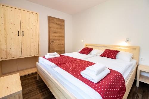 een slaapkamer met een groot bed met rode en witte lakens bij Bohinj Apartments Goldhorn Kingdom in Bohinj