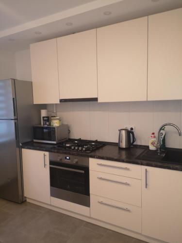 a kitchen with white cabinets and a stove top oven at Parko apartamentai in Panevėžys