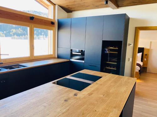 cocina con armarios azules y mesa de madera en AlpinLodge Flachau, en Flachau