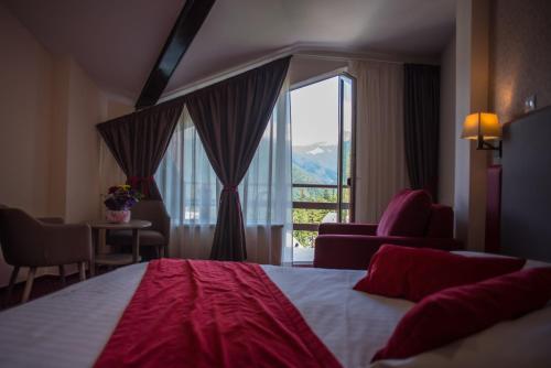 ein Hotelzimmer mit einem Bett und einem großen Fenster in der Unterkunft Hotel Marea Neagra in Sinaia