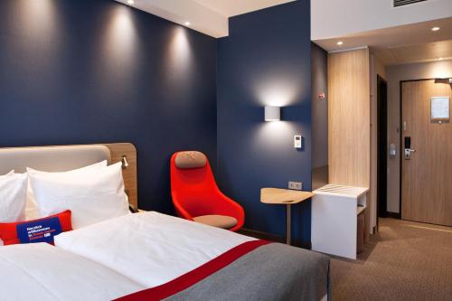 une chambre d'hôtel avec un lit et un fauteuil rouge dans l'établissement Holiday Inn Express - Darmstadt, an IHG Hotel, à Darmstadt