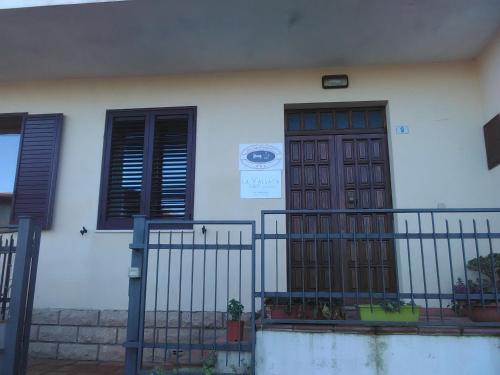 a white house with a wooden door and windows at La Vallata B&B in Sardegna in Ghilarza