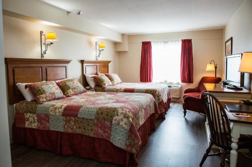 a hotel room with two beds and a desk at The Village Inn of Lakefield in Lakefield