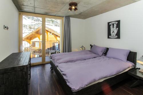 een slaapkamer met een bed met paarse lakens en een raam bij House Mojo in Zermatt