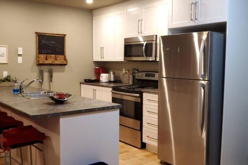 een keuken met een roestvrijstalen koelkast en witte kasten bij 1-Bedroom Apartment Bellisimo AG by Amazing Property Rentals in Gatineau