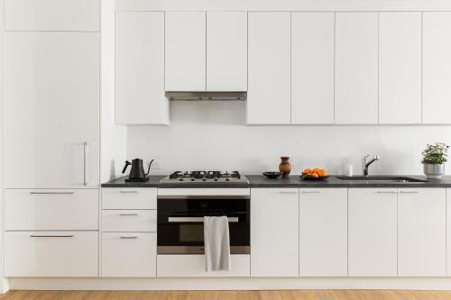 a kitchen with white cabinets and a stove at  Liz by Black Swan - DC Executive Flat in Washington