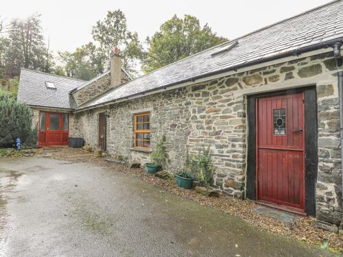 een oud stenen huis met rode deuren en een oprit bij Felin Iago in Aberystwyth