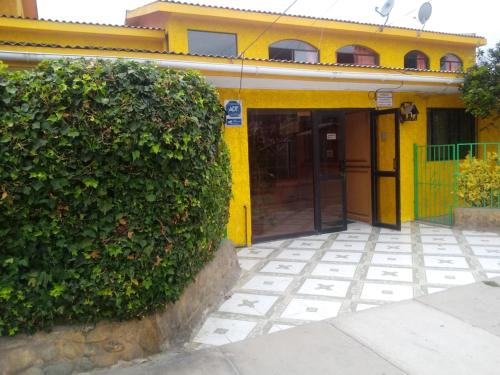 un bâtiment jaune avec un grand bush devant lui dans l'établissement Hotel San Juan, à Coquimbo