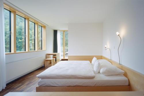 um quarto com uma cama com lençóis brancos e janelas em seehaus forelle haeckenhaus em Ramsen