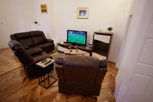 sala de estar con 2 sillas y TV en Little Vienna Gold Apartment, en Varaždin