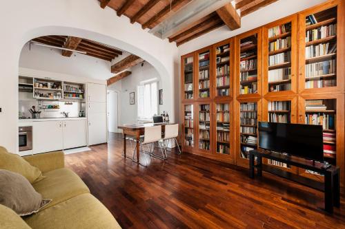 a living room with a couch and a tv and books at The Galileo Apartment in Pisa