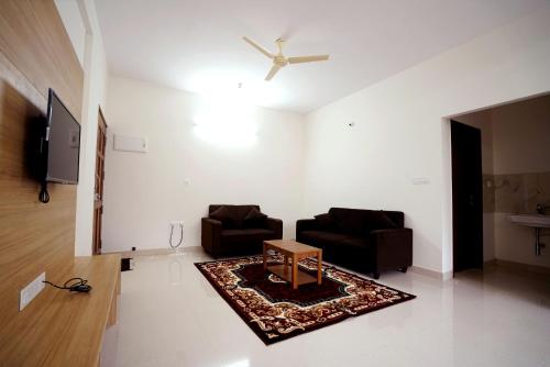 a living room with two chairs and a table at Castle JP Service Apartments in Bangalore