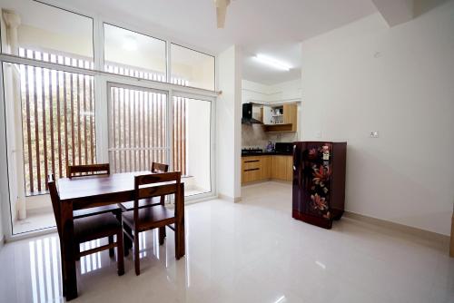 a dining room with a table and chairs and a kitchen at Castle JP Service Apartments in Bangalore