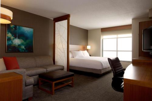 Hyatt Place Lincoln/Downtown-Haymarket في لينكولن: غرفه فندقيه بسرير واريكه