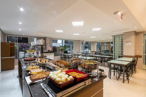 un buffet de comida en un restaurante con mesas y sillas en Hotel Negrini, en Balneário Camboriú