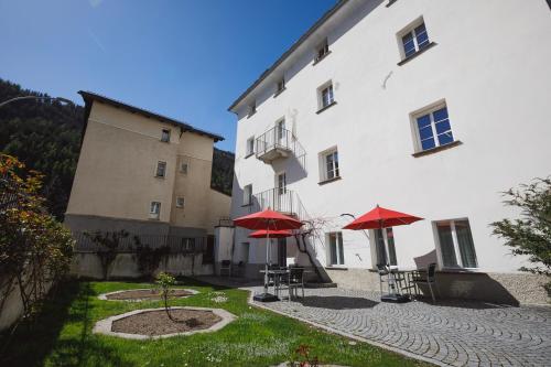 un edificio con dos sombrillas rojas delante de él en Ca' del Borgo, Rooms & Suites, en Poschiavo