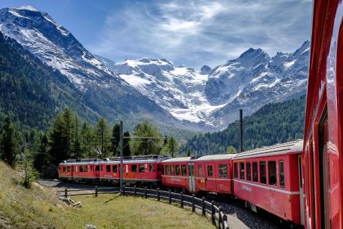 Un tren rojo está viajando por las montañas en Ca' del Borgo, Rooms & Suites, en Poschiavo