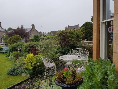 een patio met een tafel, stoelen en planten bij Moraybank Bed & Breakfast in Elgin