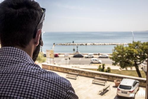 Een man die uit een raam kijkt op een parkeerplaats. bij B&B La Muraglia in Bari