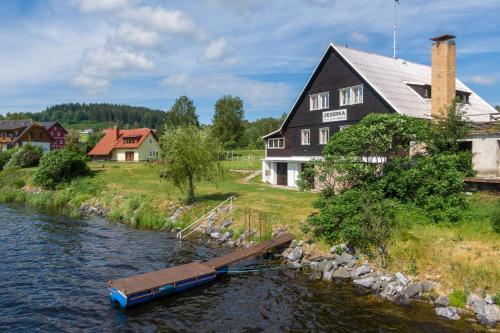 une barge sur une rivière devant une maison dans l'établissement Marvelous lake view apartments - Jezerka Lipno, à Přední Výtoň