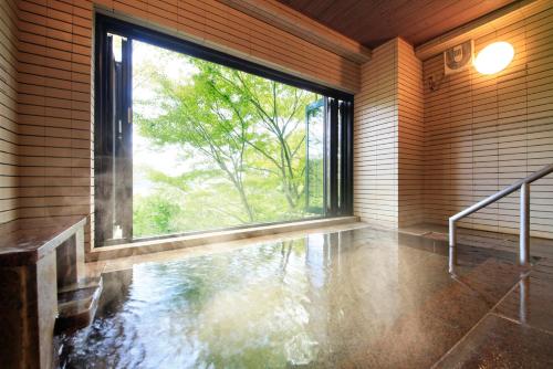 une chambre vide avec une grande fenêtre et de l'eau au sol dans l'établissement Yutorelo-an ANNEX, à Hakone