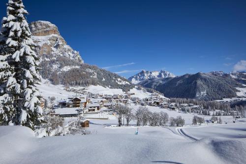 un pequeño pueblo en la nieve con una montaña en Hotel Tabladel, en Colfosco