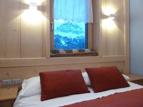 a bedroom with a bed with two pillows and a window at Albergo Chalet Lago Antorno in Misurina