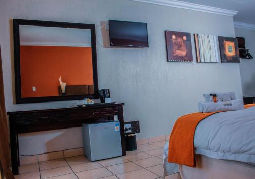 een slaapkamer met een bed en een televisie aan de muur bij Coyotes Hotel & Conference Centre in Nelspruit