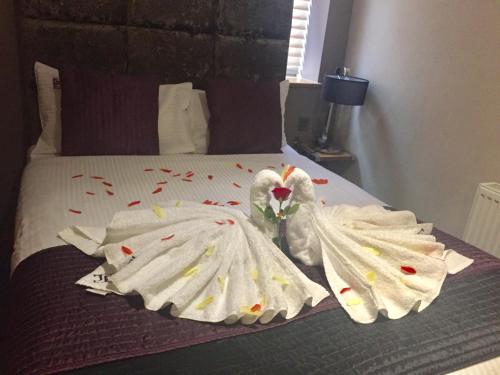 Dos cisnes vestidos de blanco están sentados en una cama en Homestay Hotel Heathrow, en Hounslow