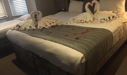 Dos cisnes están sentados en una cama con rosas. en Homestay Hotel Heathrow, en Hounslow