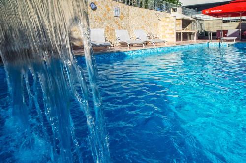 - une piscine avec un toboggan au milieu dans l'établissement Apartments Toni 2000, à Podstrana