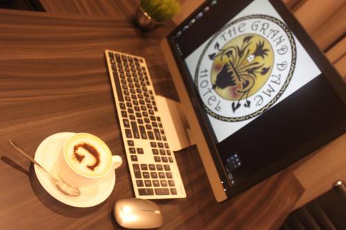 een laptop op een tafel met een kopje koffie bij The Grand Dame Hotel in Iloilo City