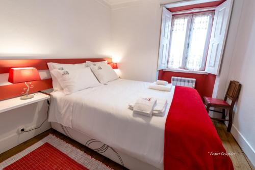 een slaapkamer met een groot wit bed met rode accenten bij Casa do Silverio - Barroca in Barroca