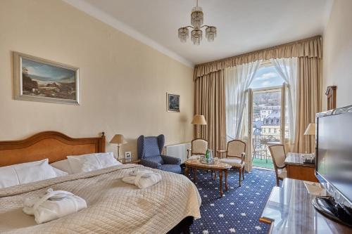 um quarto de hotel com uma cama e uma televisão em Hotel Romance em Karlovy Vary