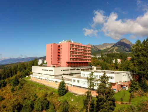 een groot gebouw op een heuvel met bergen op de achtergrond bij Hotel SOREA TRIGAN in Štrbské Pleso