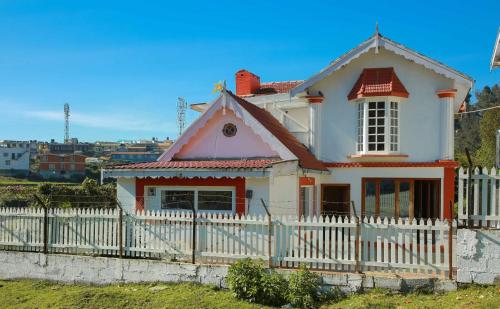 einen weißen Zaun vor einem weißen Haus in der Unterkunft Pine View Stay Ooty in Udagamandalam