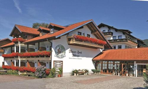 un grand bâtiment blanc avec des fleurs devant lui dans l'établissement Appart-Hotel Wildererstuben, à Bodenmais