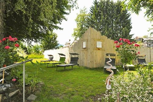 un jardin avec une clôture en bois, des chaises et des fleurs dans l'établissement Appart-Hotel Wildererstuben, à Bodenmais