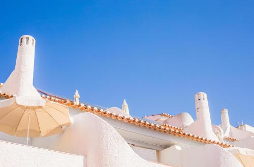 un edificio bianco con torrette e ombrello di Apartamentos Borda D´Agua ad Albufeira