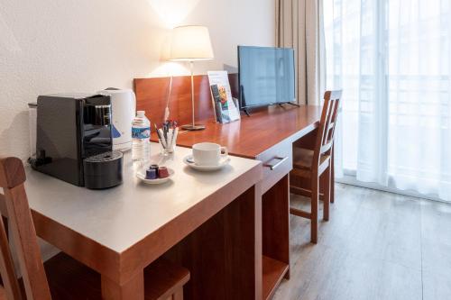 Il comprend une cuisine avec un bureau, une cafetière et une télévision. dans l'établissement Residhotel Grenette, à Grenoble